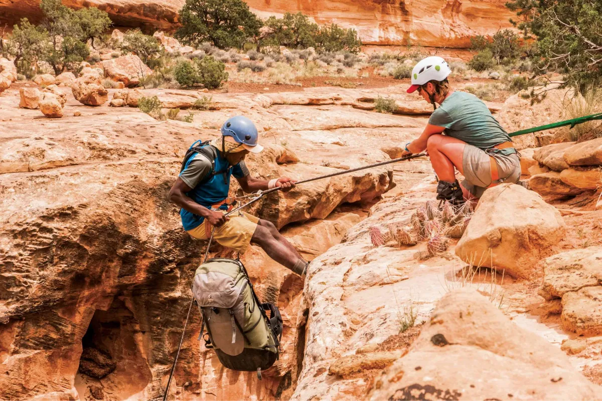 A course participant lowers themselves into a canyon while canyoneering in Utah.