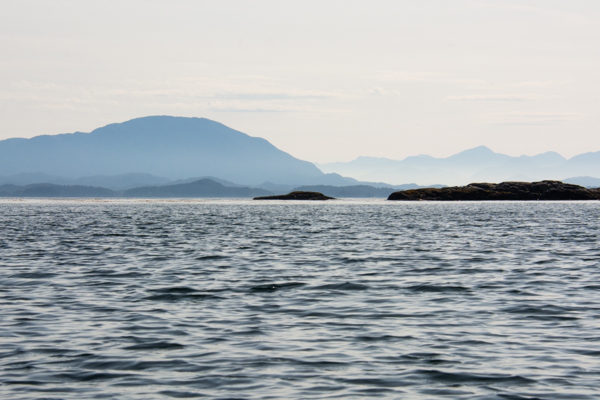 calm slate-colored water with hazy mountains in the distance