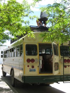 An instructor loads packs onto the top of a bus. An instructor loads packs onto the top of a bus.