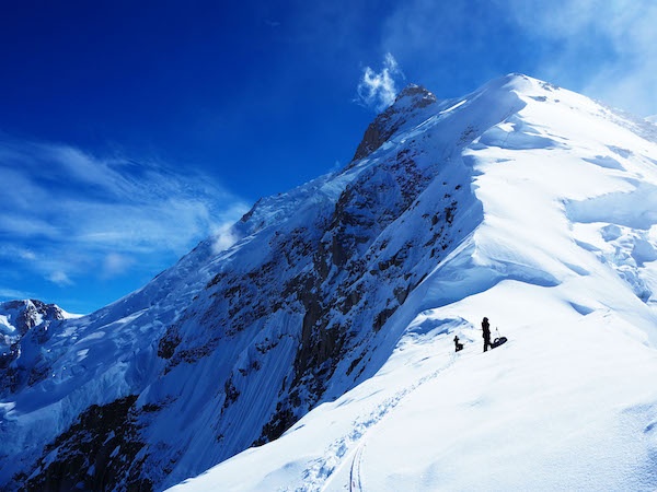 NOLS Alaska students mountaineering on Denali with sun and blue skies over snowy-covered mountains