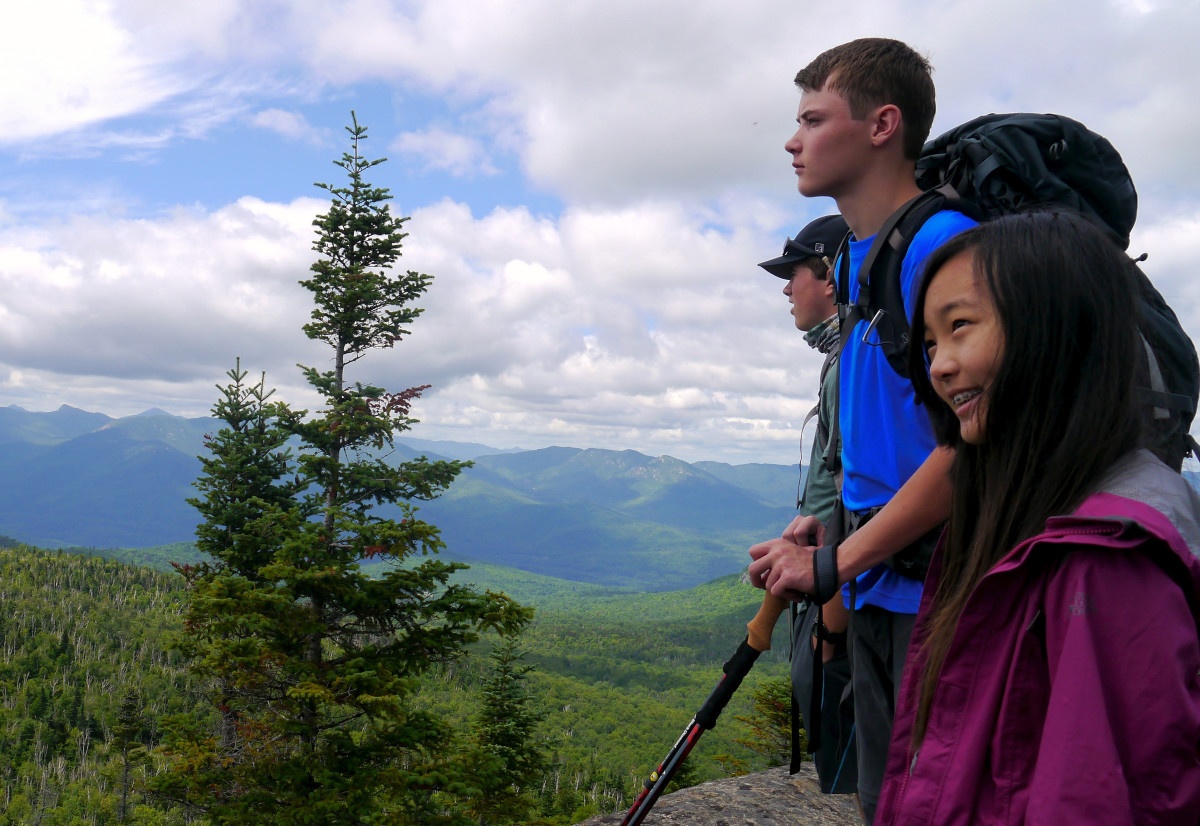 Teens look over a forested mountain ridge