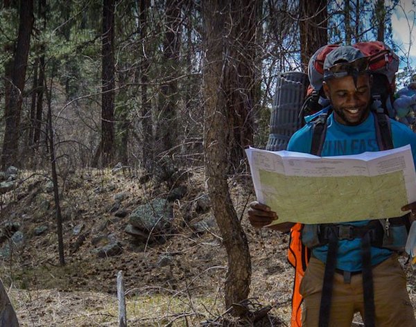 smiling NOLS student consults a map in the Southwest while backpacking