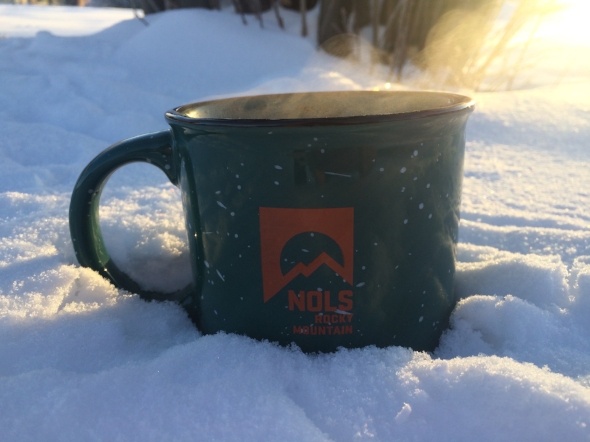 Green coffee mug steaming in the snow