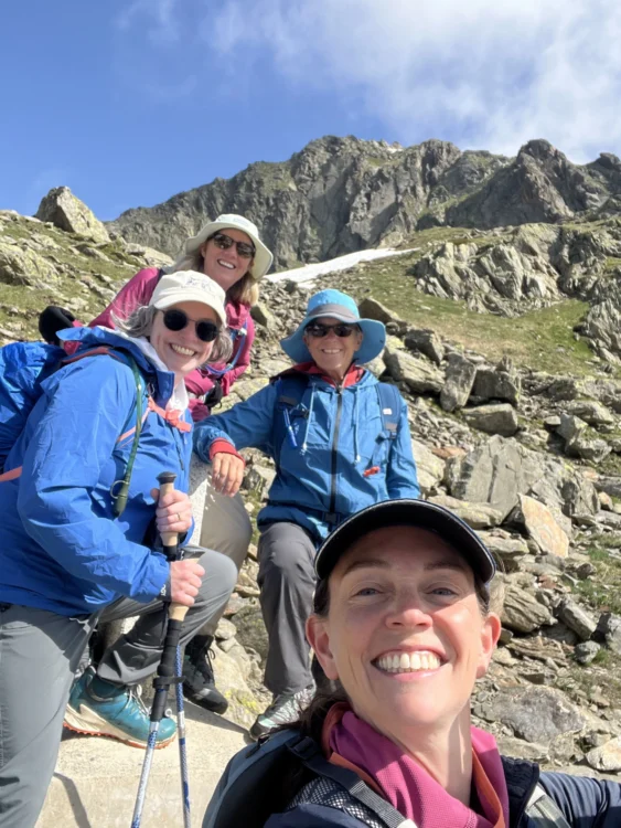 Hikers smile with mountains behind them.