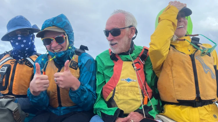 Kayakers smile while riding on a boat in Fiji