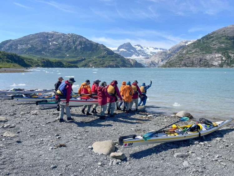 Kayakers carry boats into the water in Prince William Sound