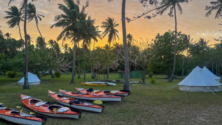 Boats line up on the grass next to tents in Fiji