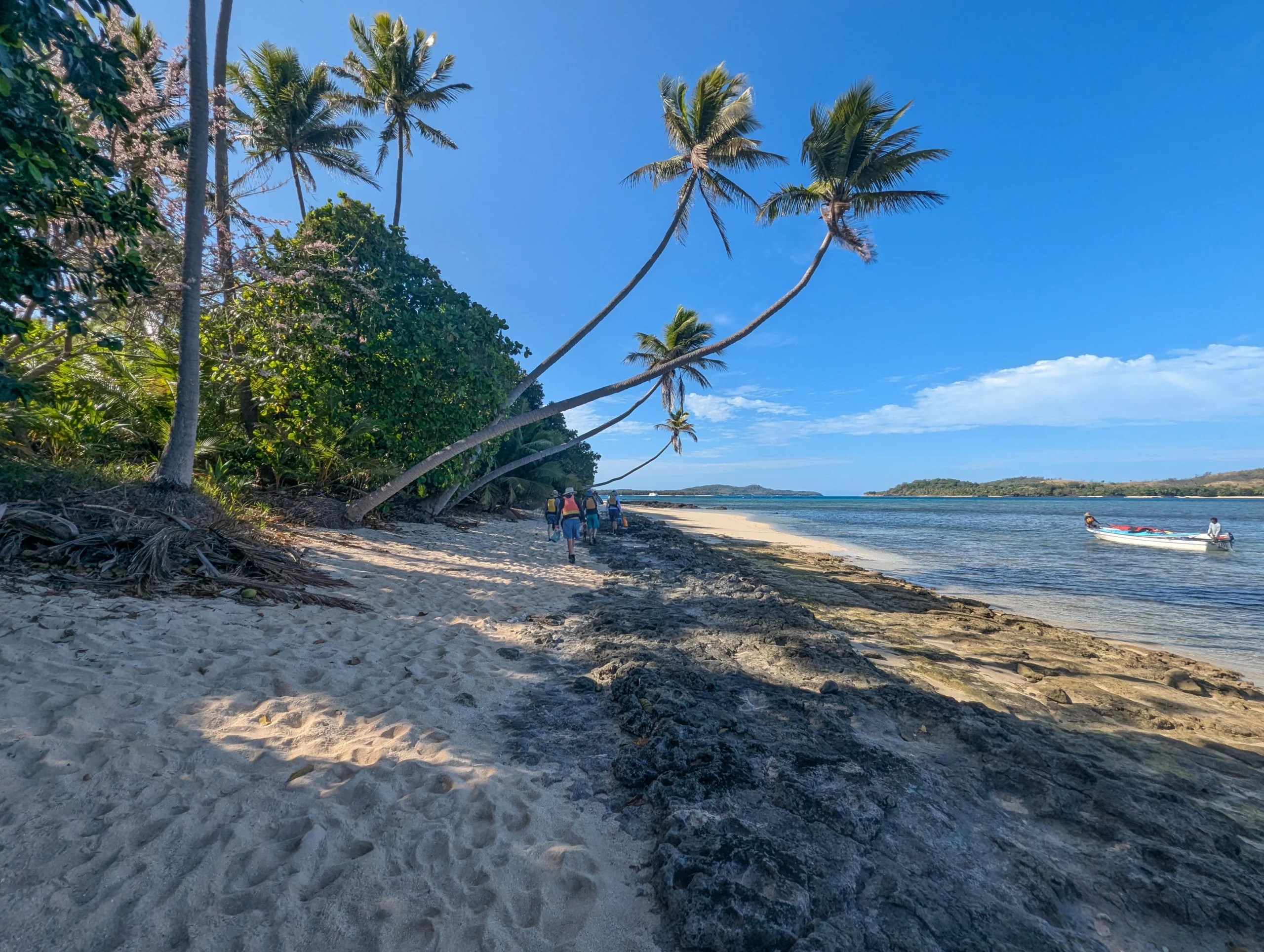 People walk down the beach in Fiji