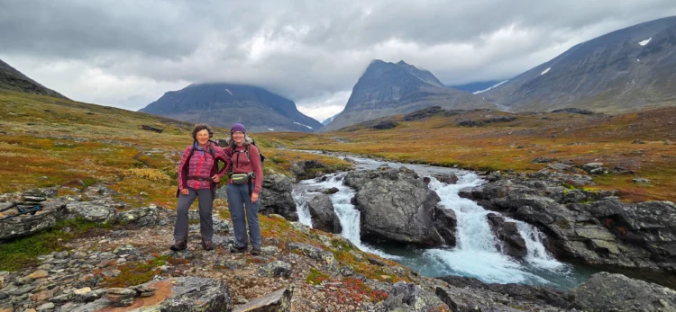 Hikers smile by a waterfall in Sweden