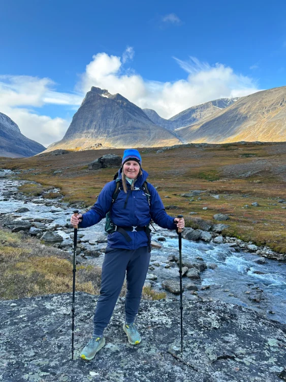 Hiker poses with towering peak in the distance